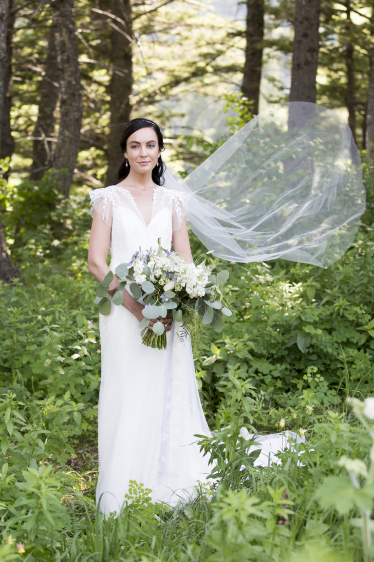 wedding photography of a bride looking back and smiling while briskly walking and her veil is flowing behind her