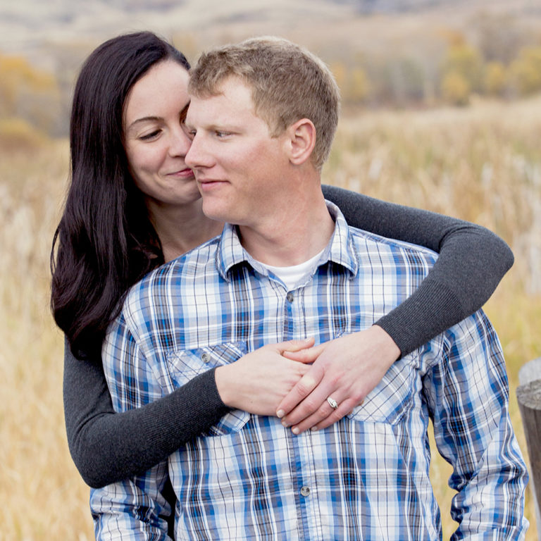 engagement photography of the bridge and groom to be bundled up in a blanket outside in a field
