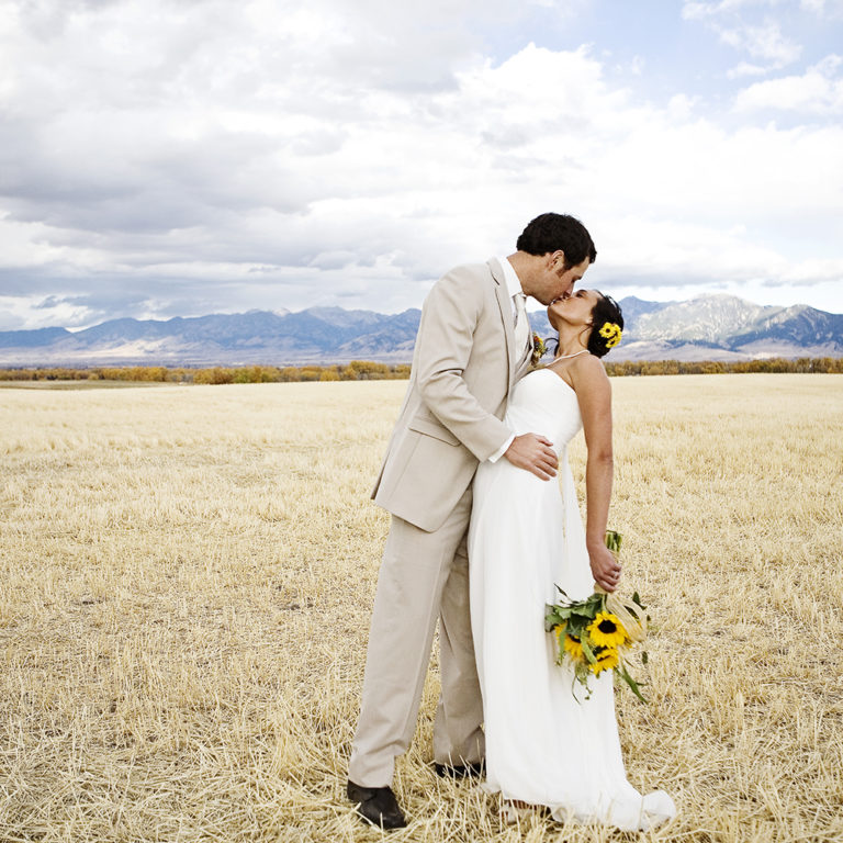 wedding photography of a bride holding her bouquet and smiling over her shoulder outside