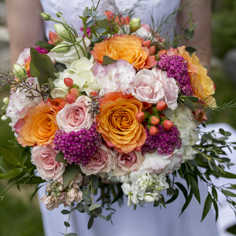 wedding photography of a bride holding her bouquet and smiling over her shoulder outside