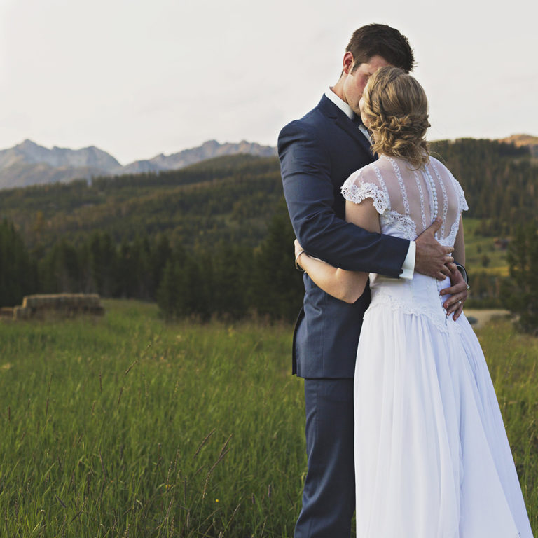 engagement photography of the bridge and groom to be bundled up in a blanket outside in a field