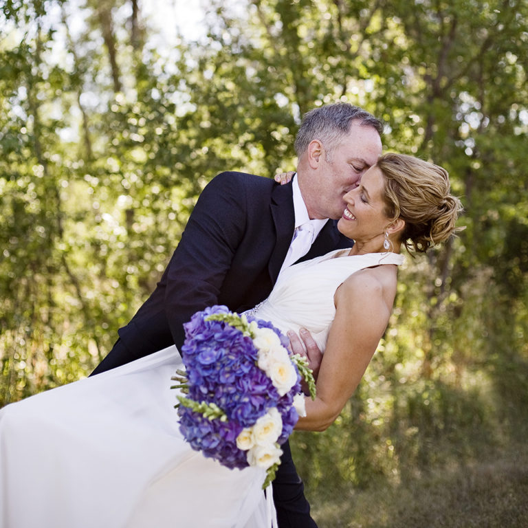 wedding photography of a bride holding her bouquet and smiling over her shoulder outside