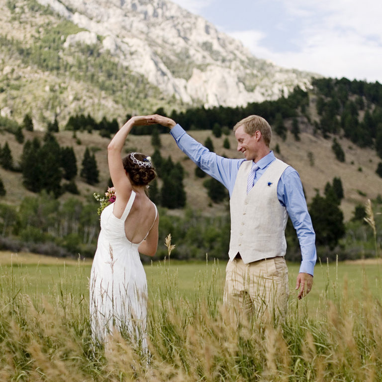 wedding photography of a bridge and groom kissing on a paved path between rows of trees outside