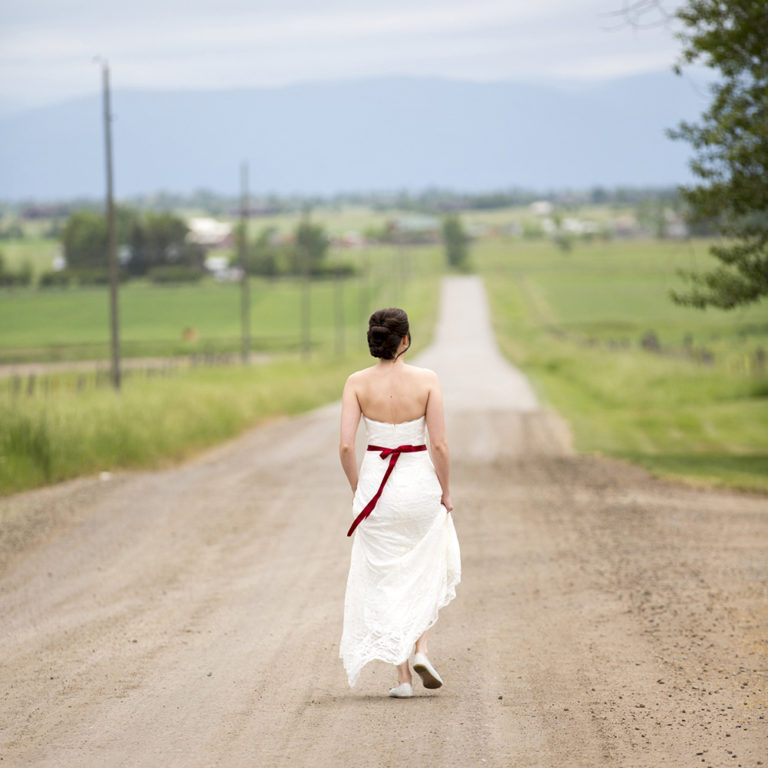 wedding photography of a bride holding her bouquet and smiling over her shoulder outside