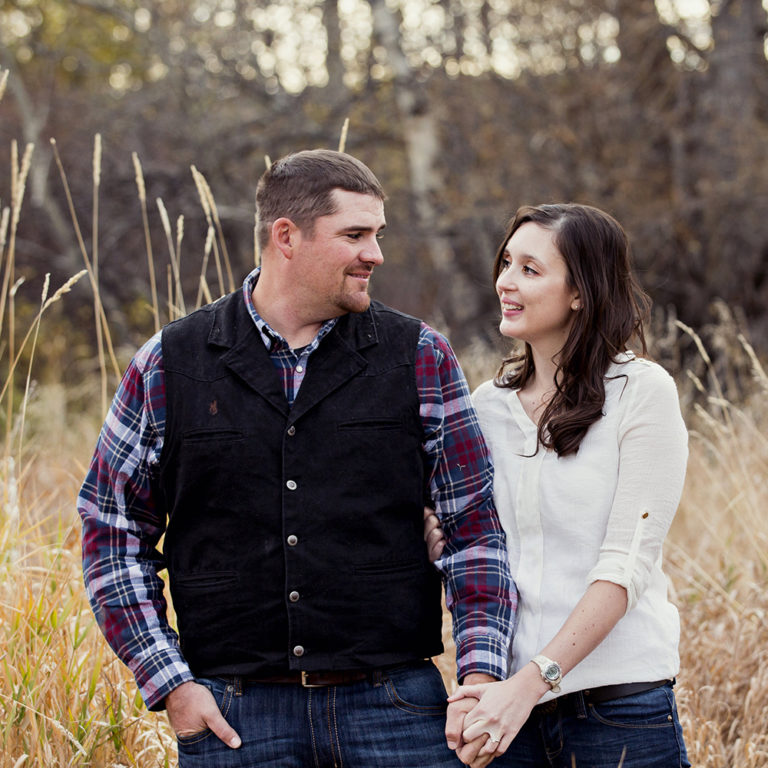 engagement photography of the bridge and groom to be bundled up in a blanket outside in a field