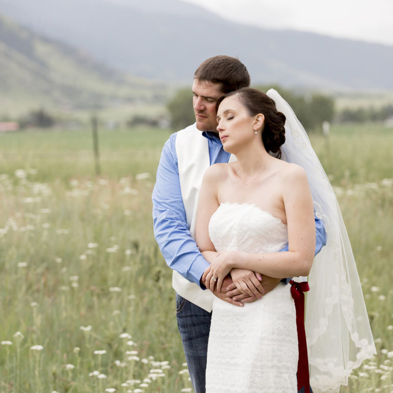 engagement photography of the bridge and groom to be bundled up in a blanket outside in a field