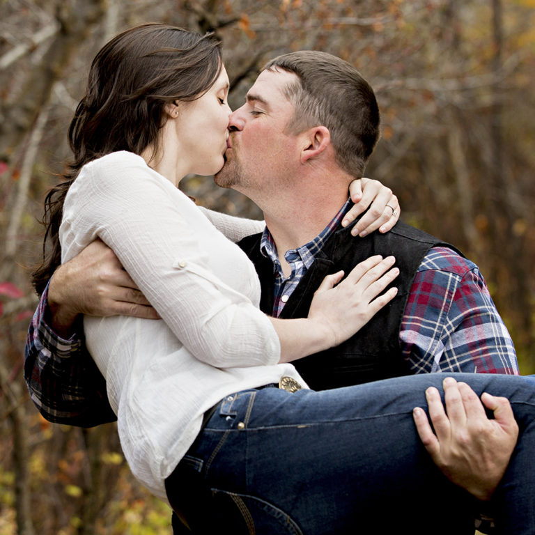 engagement photography of the bridge and groom to be bundled up in a blanket outside in a field