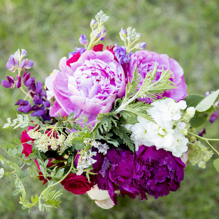 wedding photography of a bride holding her bouquet and smiling over her shoulder outside