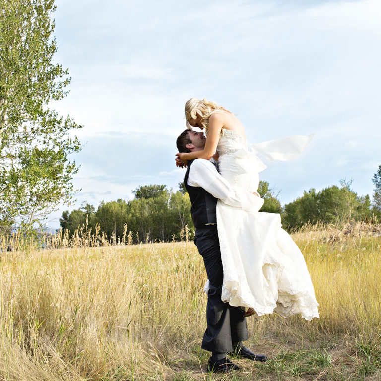 engagement photography of the bridge and groom to be bundled up in a blanket outside in a field