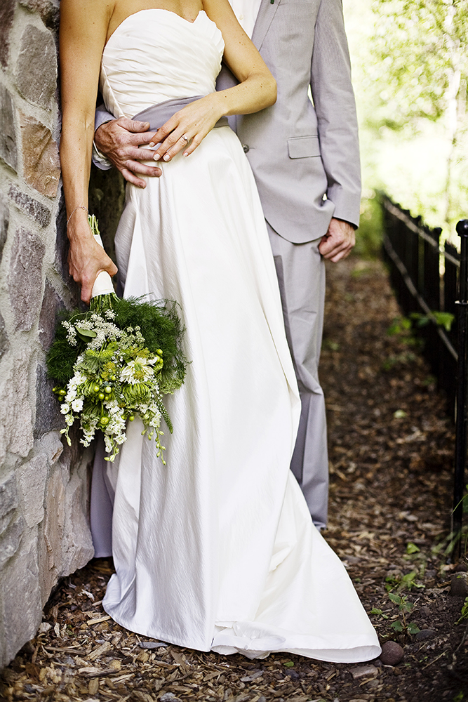 wedding photography of the bride and groom kissing while the groom uses the bride's veil for privacy outside in the field