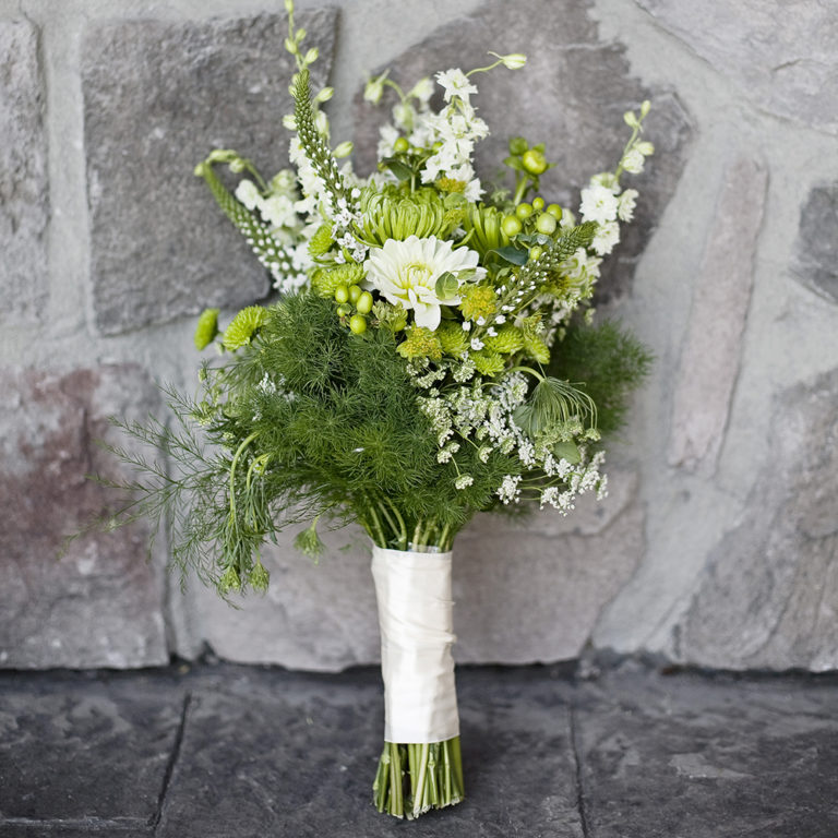 wedding photography of a bride holding her bouquet and smiling over her shoulder outside