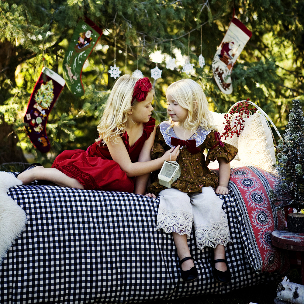 holiday portrait photography of two young sisters dressed for the holidays outside surrounded by decorations