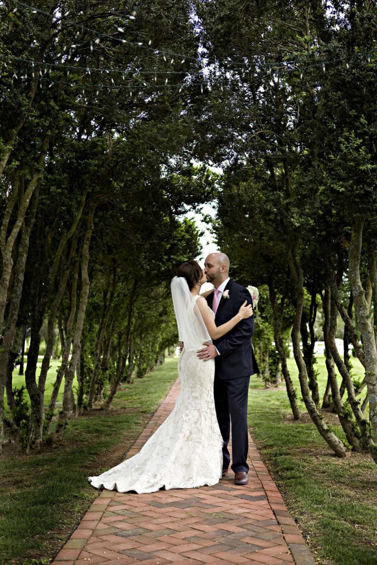 wedding photography of bride and groom's backs holding each other looking out over a lake