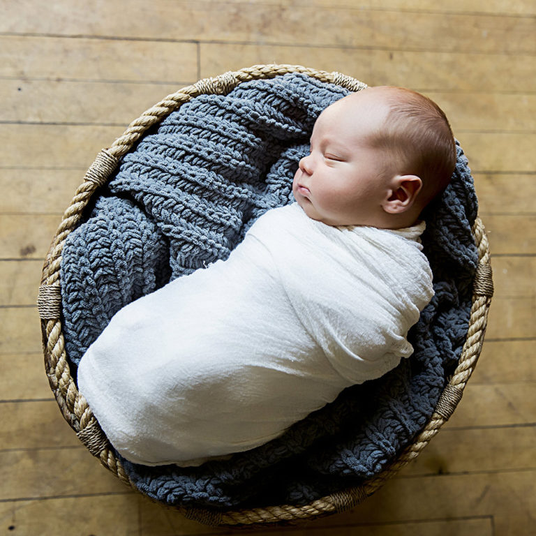 newborn photography of a new father smiling down at his newborn baby yawning in his arms