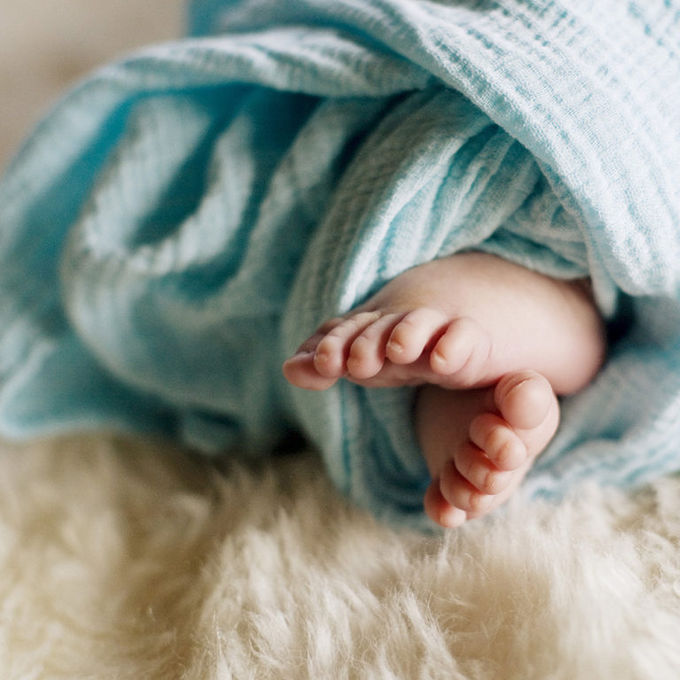 newborn photography of a newborn baby curled up sleeping on a white blanket