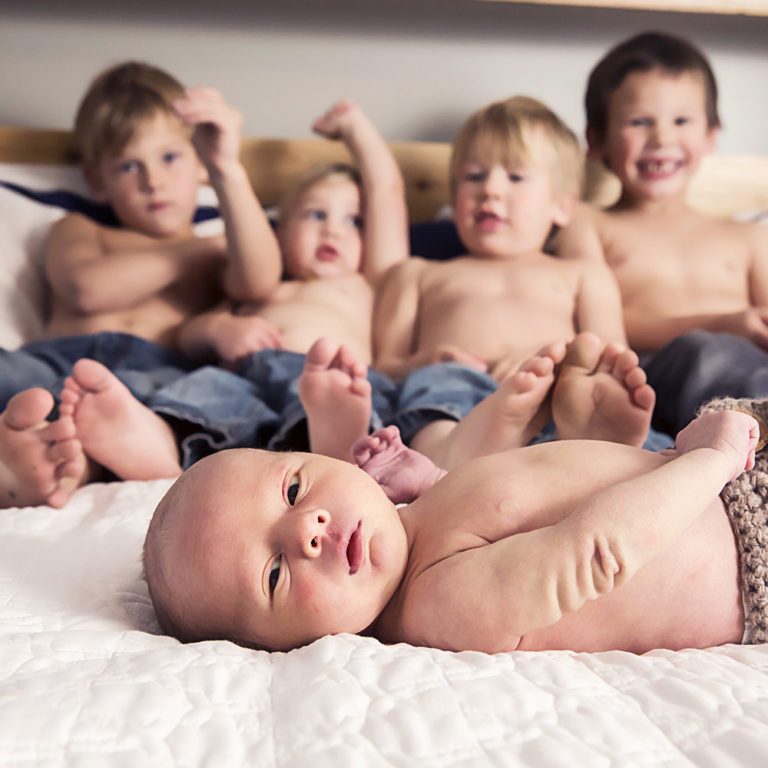 newborn photography of a new father smiling down at his newborn baby yawning in his arms