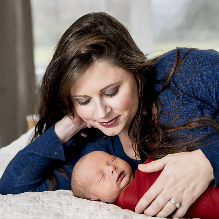 newborn photography of a newborn baby girl sleeping swaddled in a teal blanket