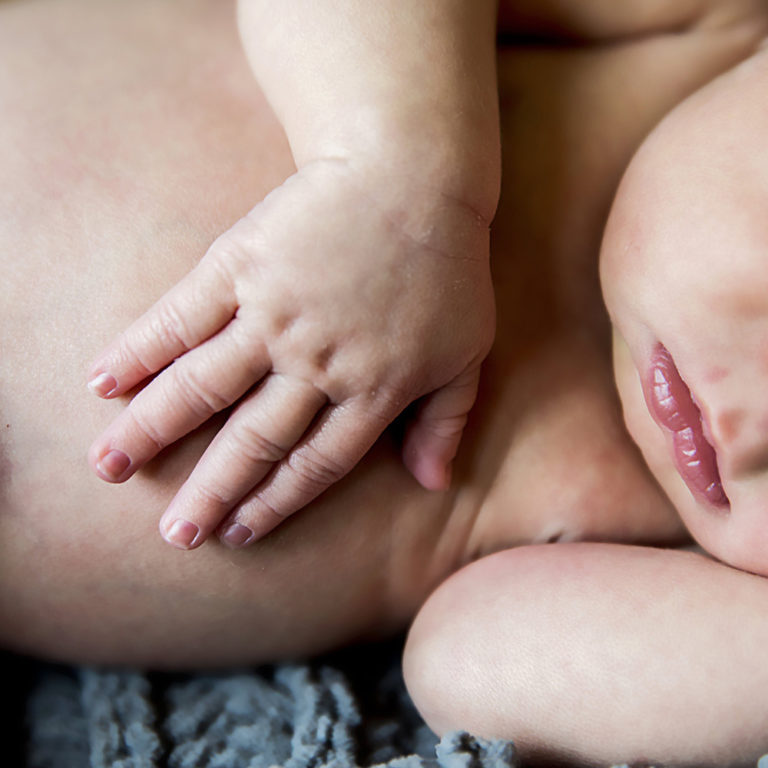 maternity photography of expectant parents holding the mothers belly while smiling at each other