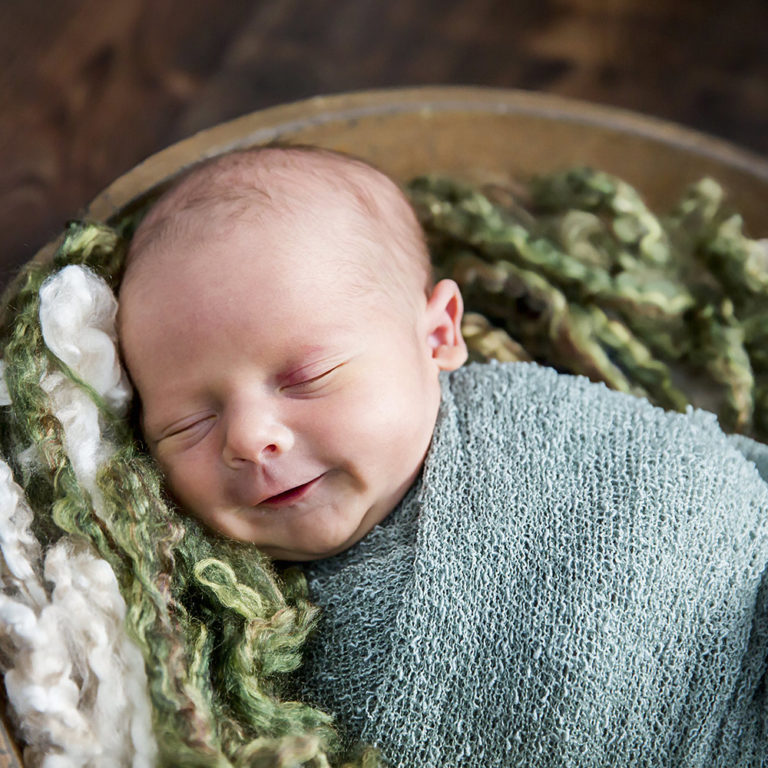 newborn photography of a newborn baby curled up sleeping on a white blanket