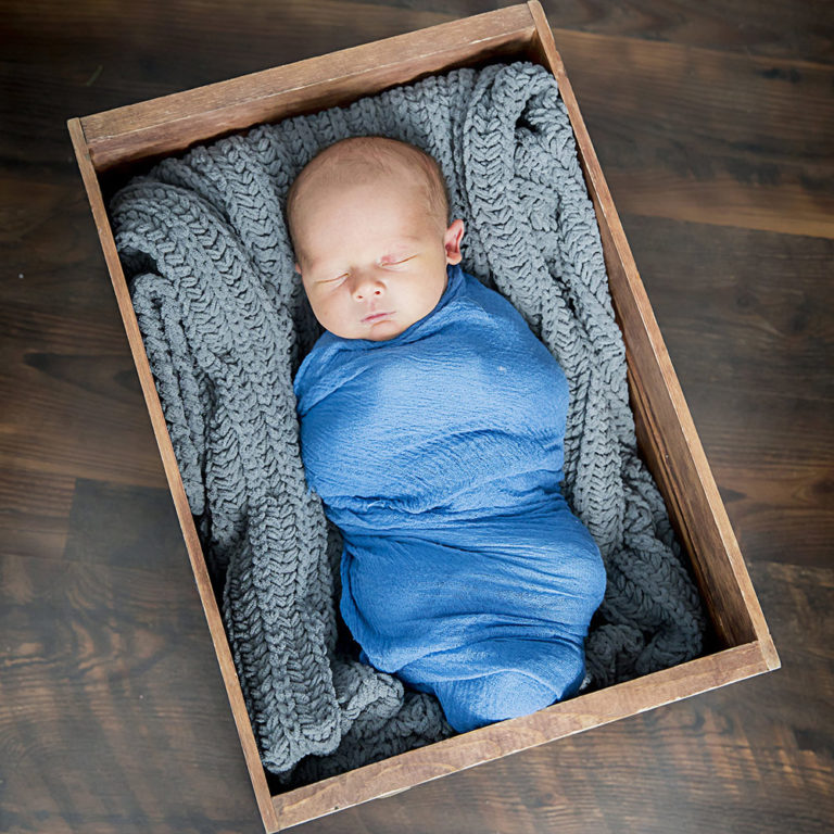 newborn photography of a newborn baby curled up sleeping on a white blanket