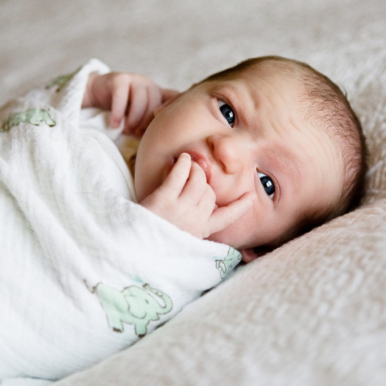 newborn photography of a new father smiling down at his newborn baby yawning in his arms