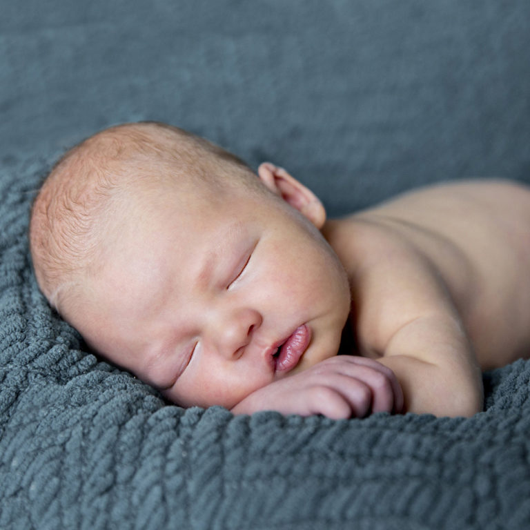 newborn photography of a newborn baby girl sleeping swaddled in a teal blanket