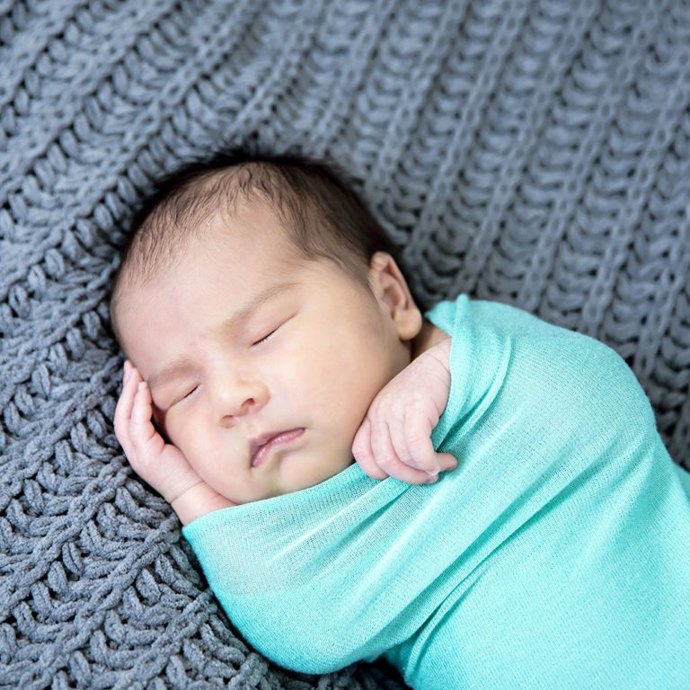 newborn photography of a newborn baby curled up sleeping on a white blanket