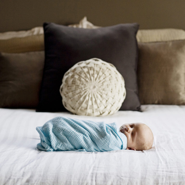 newborn photography of a newborn baby curled up sleeping on a white blanket