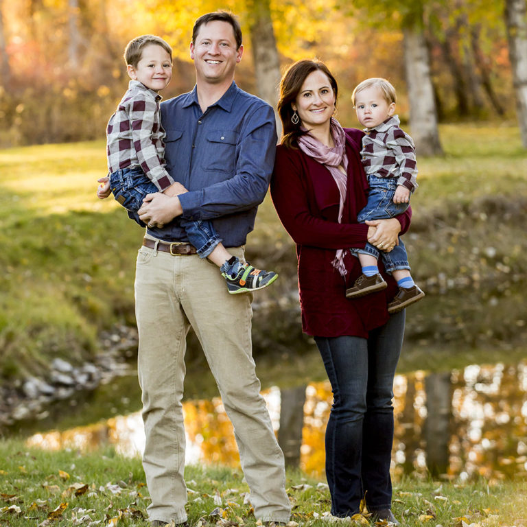 family portrait photography of a young girl holding toy arrows in front of a cabin