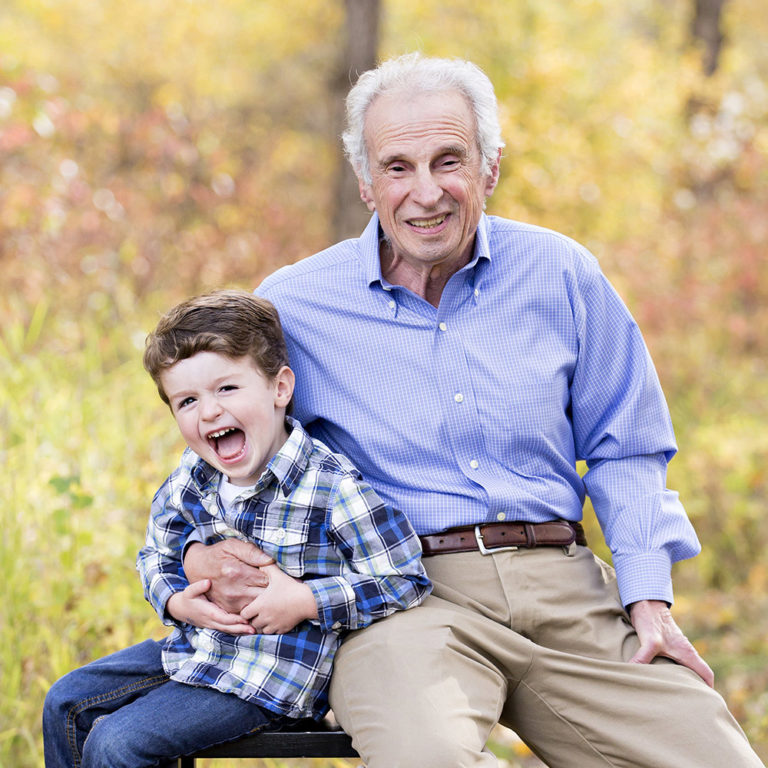 family portrait photography of a young boy smiling wide with his eyes closed outside