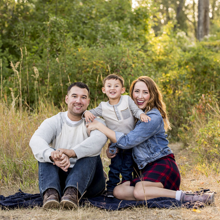 family portrait photography of three sisters standing in front of a brick wall and blowing flower petals out of their hands