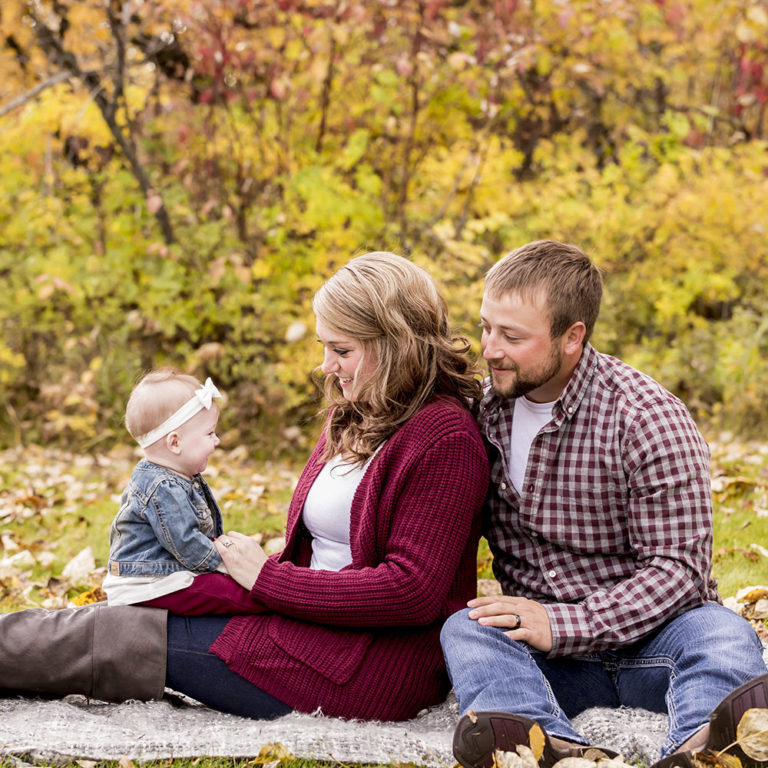 family portrait photography of a young girl holding toy arrows in front of a cabin