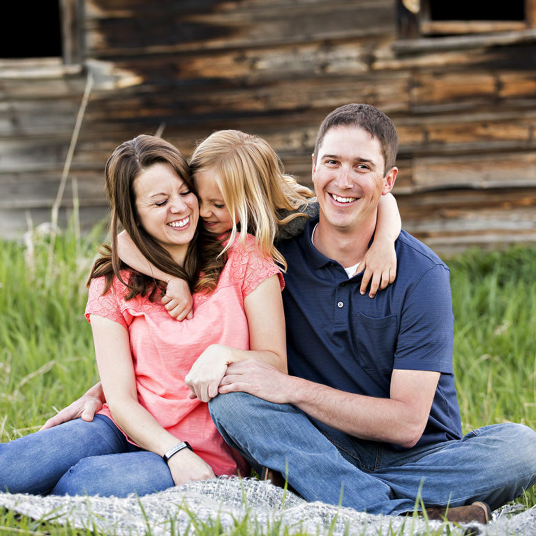 family portrait photography of a young girl holding toy arrows in front of a cabin