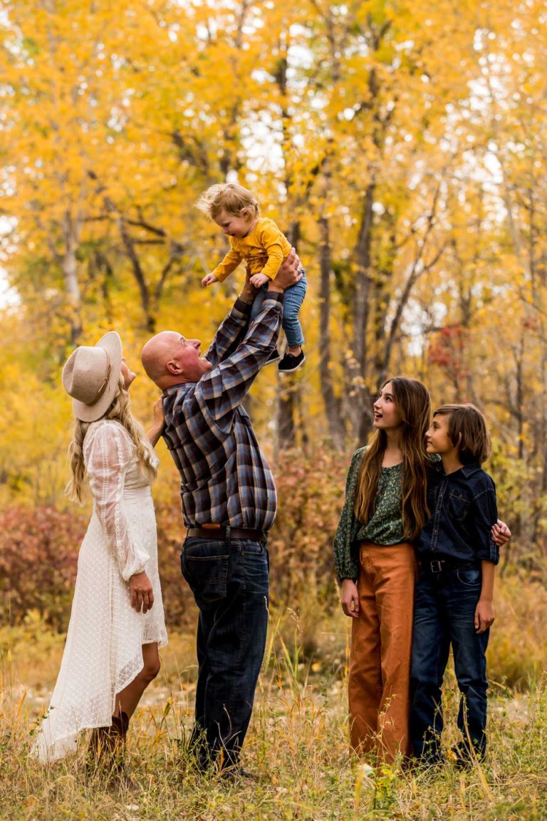 family portrait photography of a young boy smiling wide with his eyes closed outside