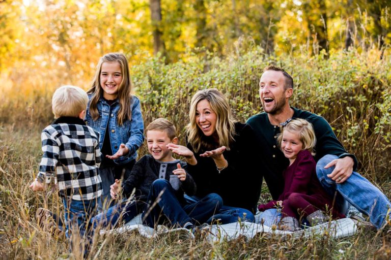 family portrait photography of a young girl holding toy arrows in front of a cabin