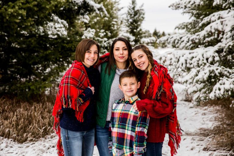 family portrait photography of a young girl holding toy arrows in front of a cabin