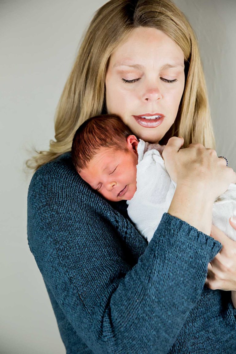 newborn photography of a new father smiling down at his newborn baby yawning in his arms