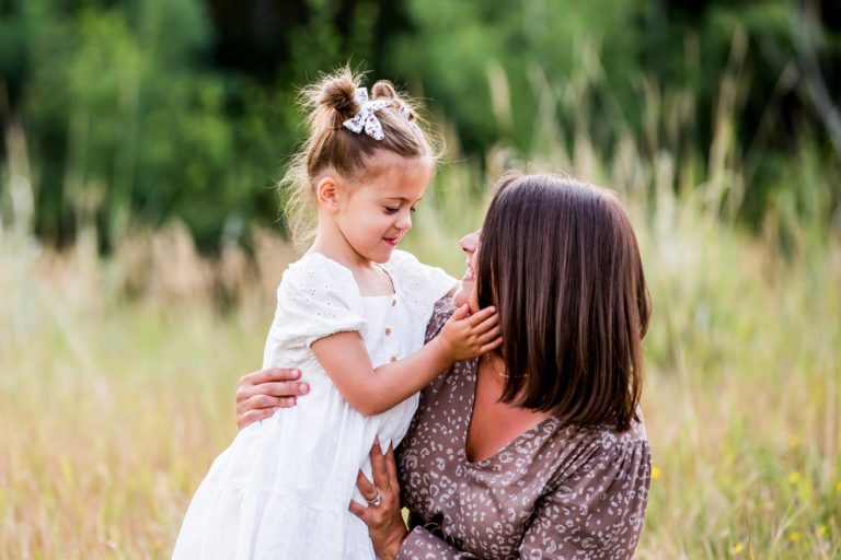 family portrait photography of a young boy smiling wide with his eyes closed outside