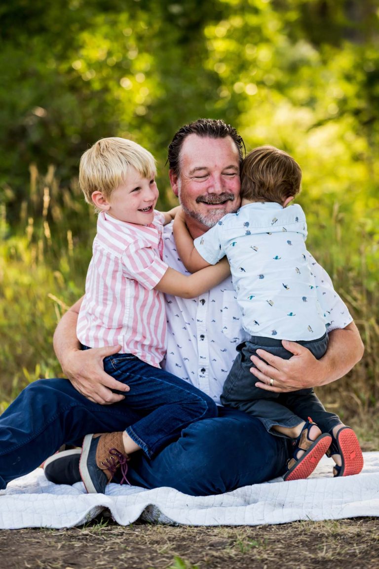 family portrait photography of a young boy smiling wide with his eyes closed outside