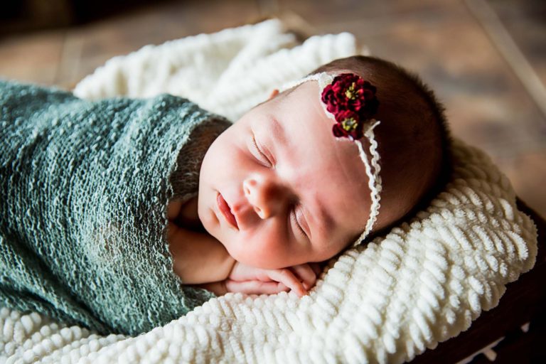 newborn photography of a newborn baby curled up sleeping on a white blanket