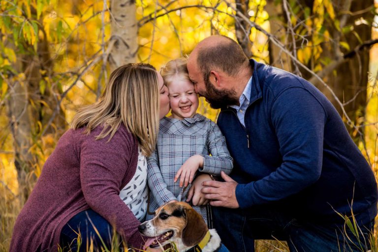 family portrait photography of a young girl holding toy arrows in front of a cabin