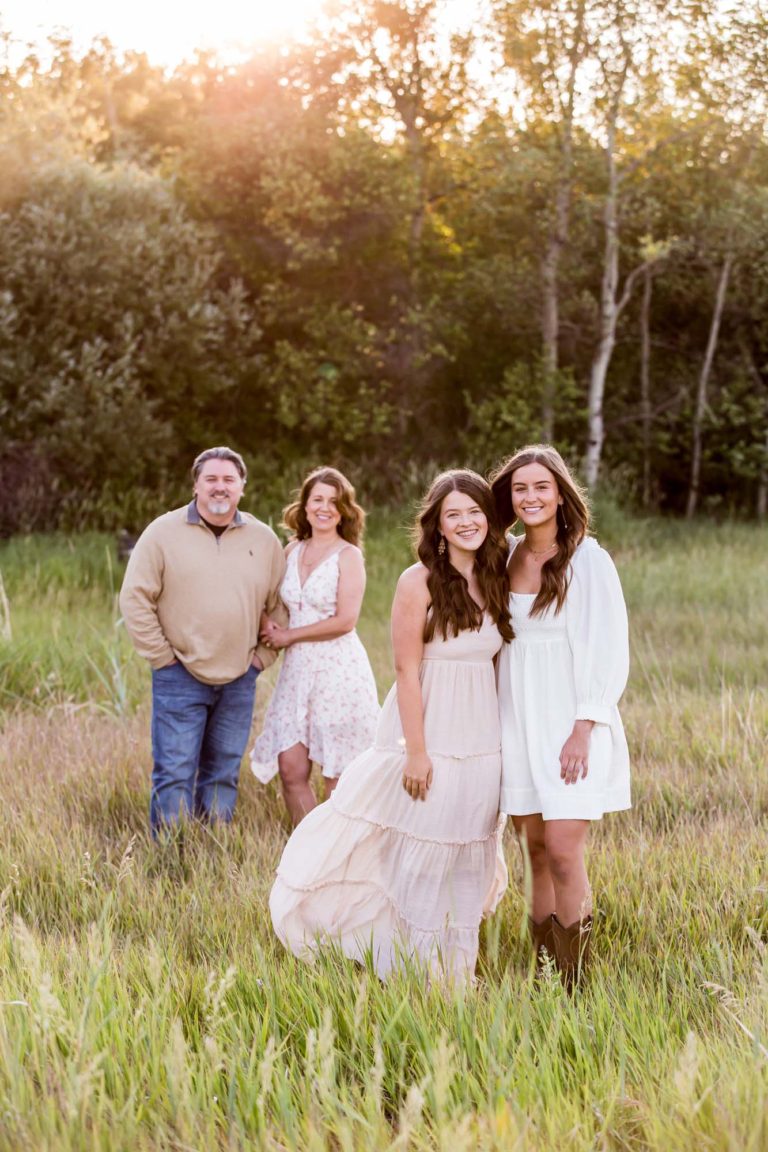 family portrait photography of three sisters standing in front of a brick wall and blowing flower petals out of their hands