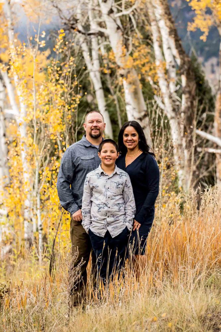 family portrait photography of a mother, father, and teenage daughter walking hand in hand through a field