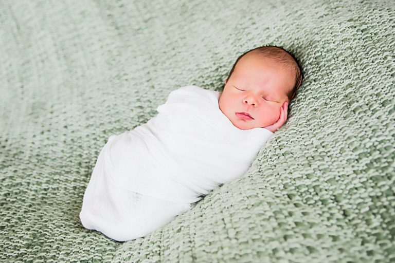 newborn photography of a new father smiling down at his newborn baby yawning in his arms