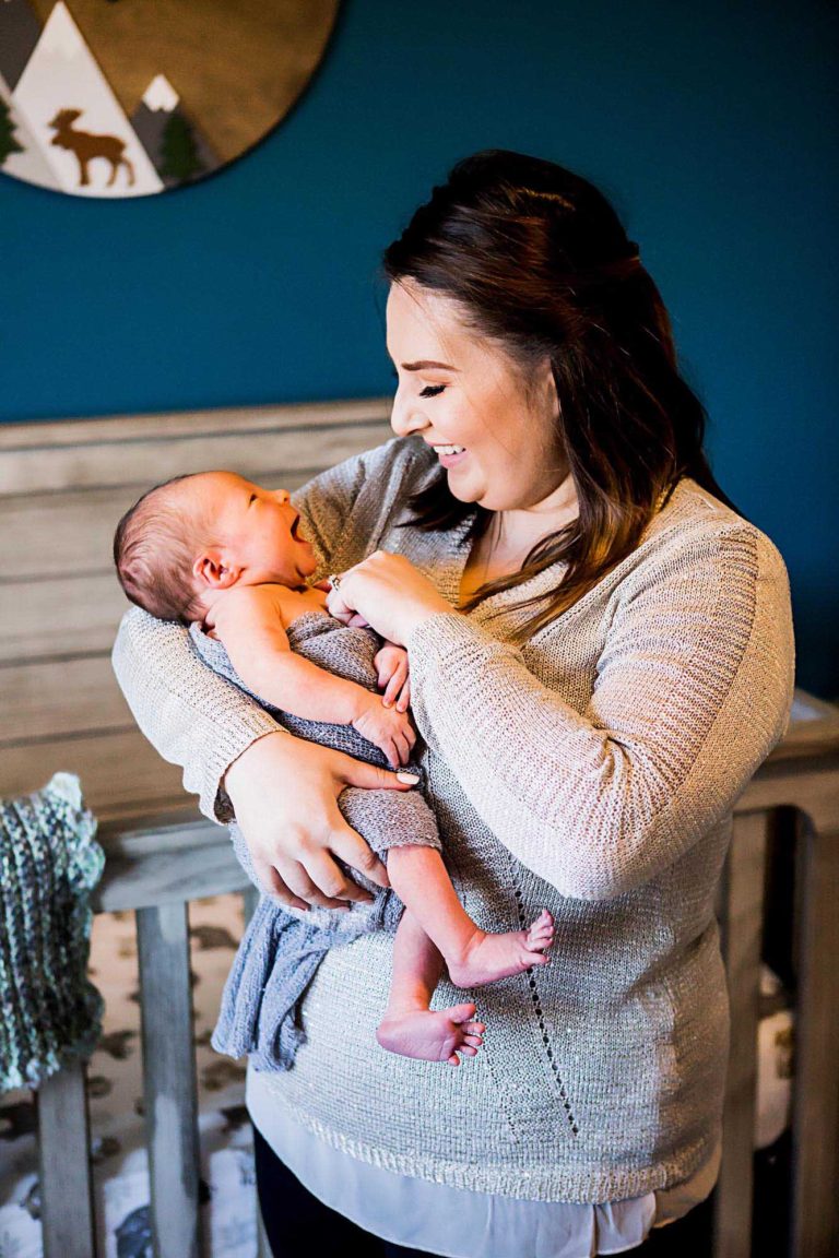 newborn photography of a new father smiling down at his newborn baby yawning in his arms