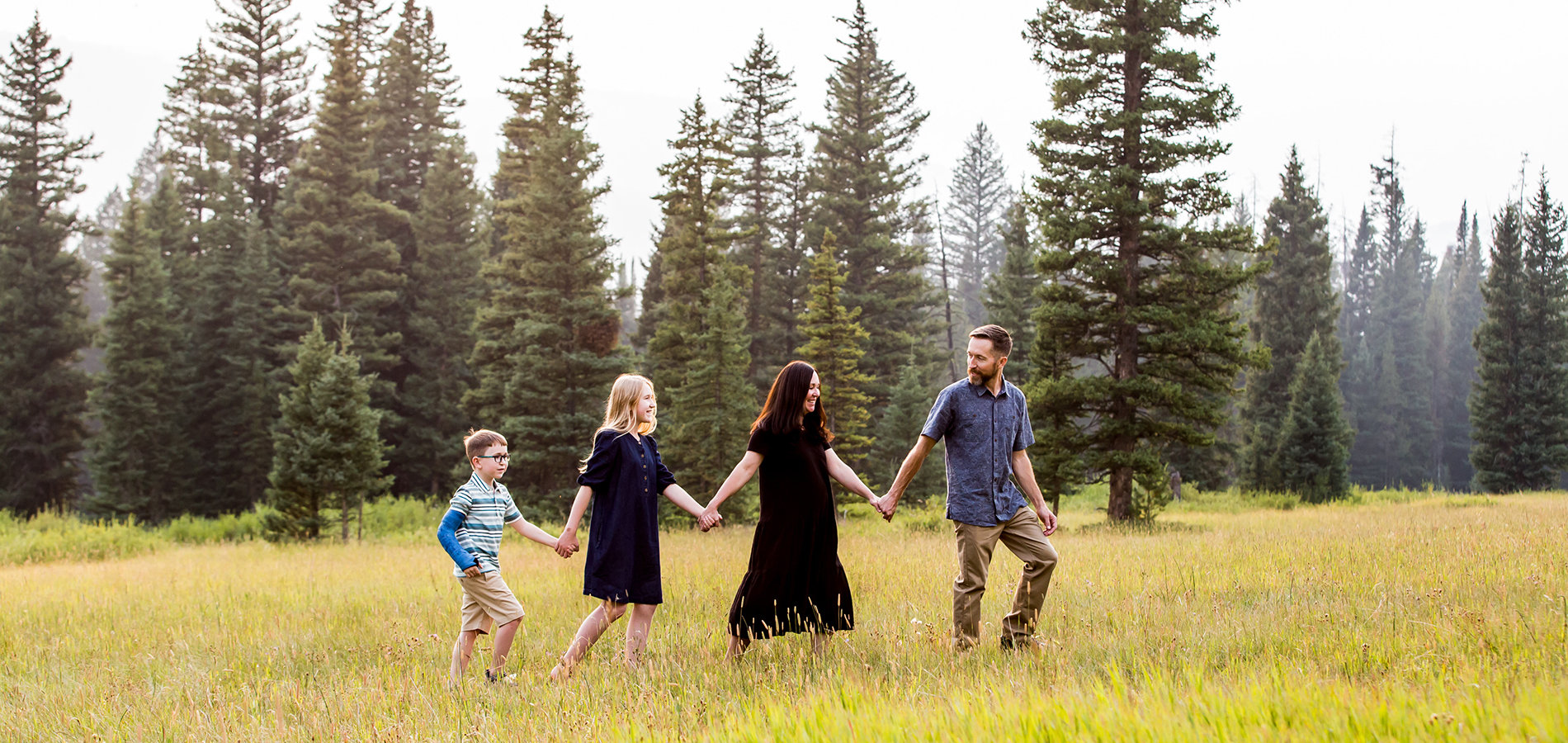 Family of four walking in field captured by Bozeman photographer.