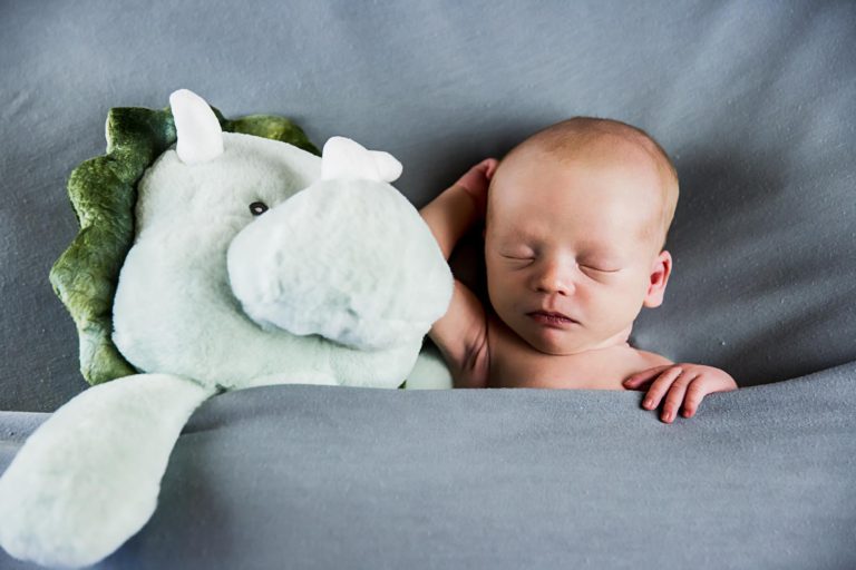 newborn photography of a newborn baby curled up sleeping on a white blanket