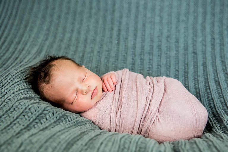 newborn photography of a newborn baby curled up sleeping on a white blanket