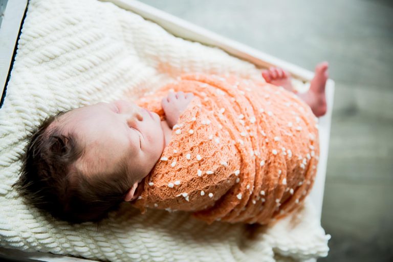 newborn photography of a new father smiling down at his newborn baby yawning in his arms