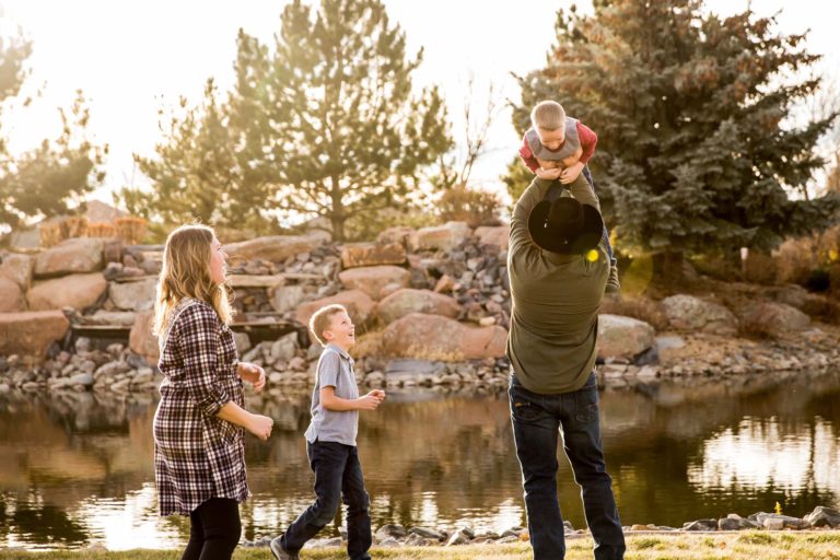 Dad lifting son in air while mom and older brother watch